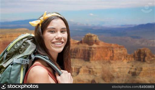 adventure, travel, tourism, hike and people concept - smiling young woman with backpack over grand canyon national park background. happy woman with backpack over grand canyon. happy woman with backpack over grand canyon