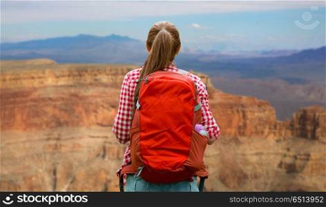 adventure, travel, tourism, hike and people concept - smiling young woman with backpack over grand canyon national park background. smiling woman with backpack over grand canyon. smiling woman with backpack over grand canyon