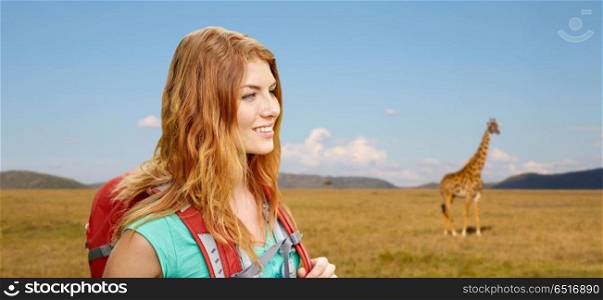 adventure, travel, tourism, hike and people concept - smiling young woman with backpack over giraffe in african savannah background. happy woman with backpack over african savannah. happy woman with backpack over african savannah