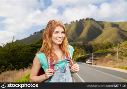 adventure, travel, tourism, hike and people concept - smiling young woman with backpack over big sur hills of california background. smiling woman with backpack over big sur hills. smiling woman with backpack over big sur hills