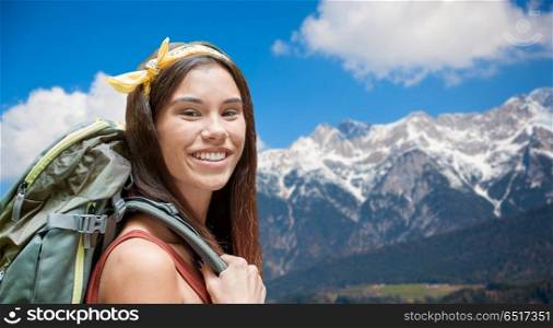 adventure, travel, tourism, hike and people concept - smiling young woman with backpack over alps mountains background. happy woman with backpack over alps mountains. happy woman with backpack over alps mountains