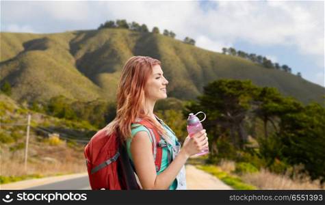 adventure, travel, tourism, hike and people concept - smiling young woman with backpack and bottle of water over big sur of california hills background. smiling woman with backpack on big sur hills. smiling woman with backpack on big sur hills