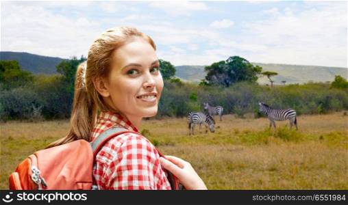 adventure, travel, tourism, hike and people concept - smiling young woman with backpack over zebras in african savannah background. happy woman with backpack over african savannah. happy woman with backpack over african savannah