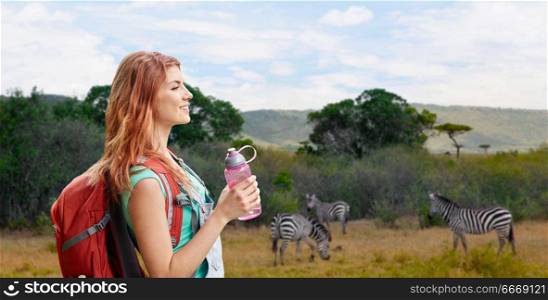 adventure, travel, tourism, hike and people concept - smiling young woman with backpack and bottle of water over zebras in african savannah background. happy woman with backpack over african savannah. happy woman with backpack over african savannah
