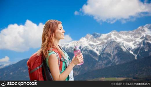 adventure, travel, tourism, hike and people concept - smiling young woman with backpack and bottle of water over alps mountains background. smiling woman with backpack over alps mountains. smiling woman with backpack over alps mountains