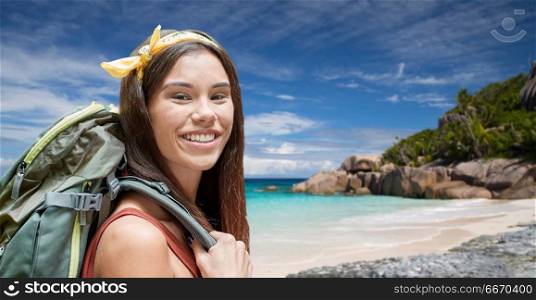 adventure, travel, tourism, hike and people concept - smiling young woman with backpack over background of seychelles island beach in indian ocean. happy woman with backpack over seychelles beach. happy woman with backpack over seychelles beach