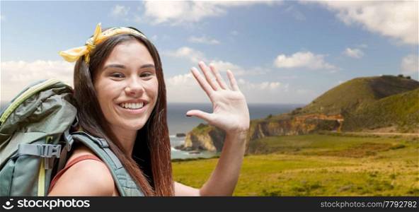 adventure, travel, tourism, hike and people concept - smiling young woman with backpack over big sur coast of california background. smiling woman with backpack on big sur coast