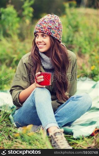 adventure, travel, tourism, hike and people concept - smiling young woman with cup sitting in camping