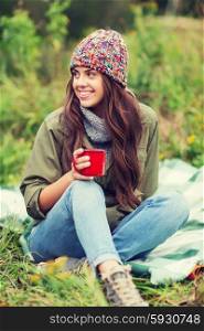 adventure, travel, tourism, hike and people concept - smiling young woman with cup sitting in camping