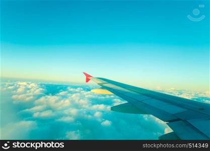 Adventure, travel, transport concept. View from plane window at sky with clouds and wing. View from plane window, cloud sky