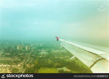Adventure, travel, transport concept. View from plane window at sky with clouds, wing and city. View from plane window. City view