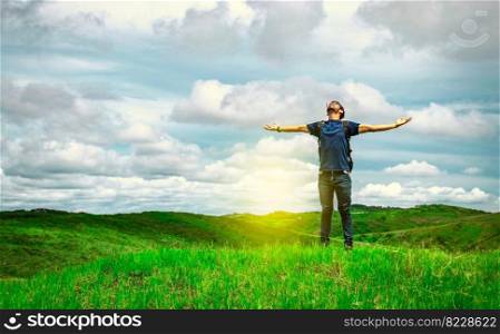 Adventurous man spreading his arms in the countryside. Man with backpack on a hill spreading his arms. Explorer man spreading his arms on a hill. Lifestyle of adventurous man in the field