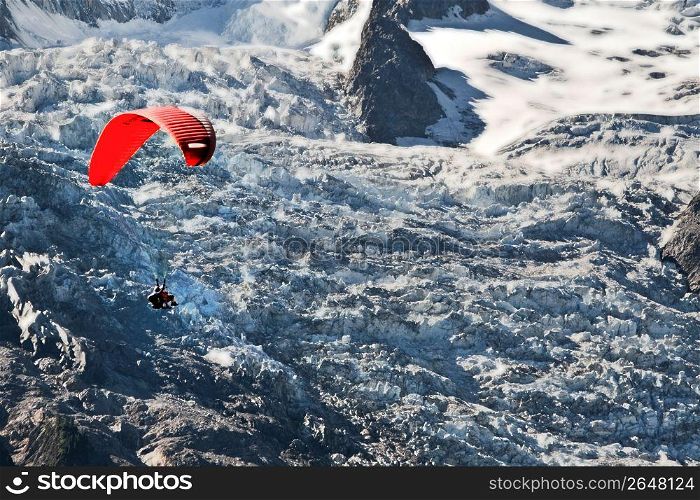 Adventurous paraglider paragliding over remote snow-covered mountainside