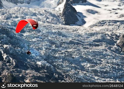 Adventurous paraglider paragliding over remote snow-covered mountainside