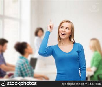advertisement and education concept - attractive young woman in casual clothes pointing her finger up