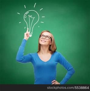 advertisement and electricity concept - attractive young woman in casual clothes and eyeglasses pointing her finger up to light bulb doodle