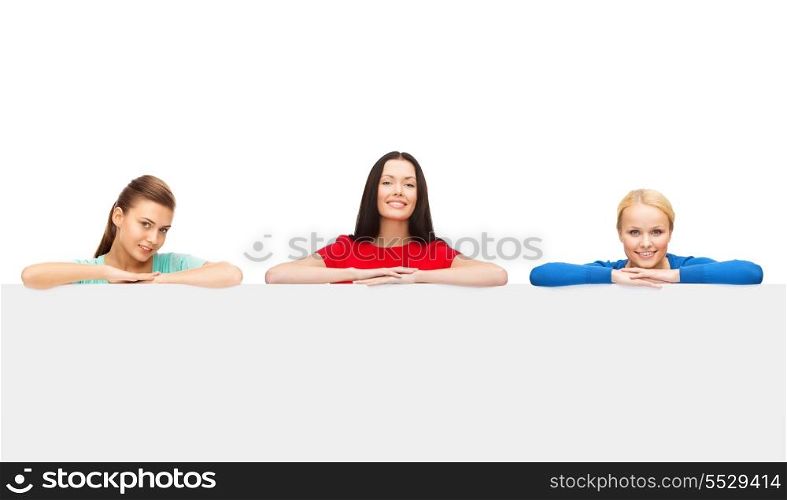 advertisement and happy people concept - three smiling women with big blank white board