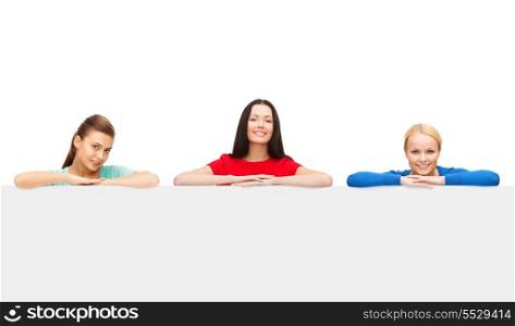advertisement and happy people concept - three smiling women with big blank white board