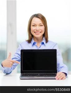 advertisement, business and technology concept - smiling businesswoman pointing finger to blank black laptop screen