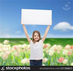 advertisement, childhood, happiness and people concept - smiling little child in white t-shirt holding blank board over blue sky and field of flowers background