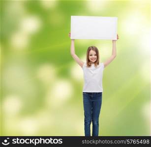 advertisement, childhood, happiness and people concept - smiling little child in white t-shirt holding blank board over green background