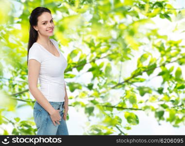 advertisement, clothing and people concept - happy smiling young woman or teenage girl in white t-shirt over green natural background