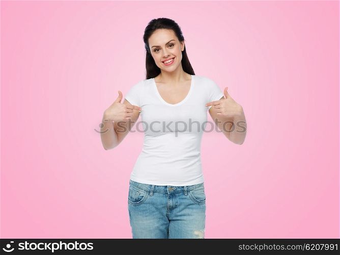 advertisement, clothing and people concept - happy smiling young woman or teenage girl in white t-shirt pointing finger to herself over pink background
