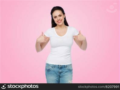 advertisement, clothing and people concept - happy smiling young woman or teenage girl in white t-shirt pointing finger to herself over pink background