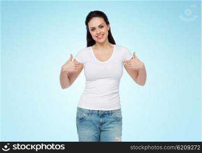 advertisement, clothing and people concept - happy smiling young woman or teenage girl in white t-shirt pointing finger to herself over blue background