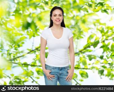advertisement, clothing and people concept - happy smiling young woman or teenage girl in white t-shirt over green natural background