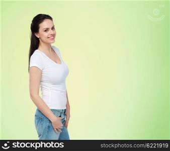 advertisement, clothing and people concept - happy smiling young woman or teenage girl in white t-shirt over green natural background