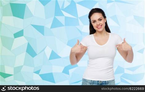 advertisement, clothing and people concept - happy smiling young woman or teenage girl in white t-shirt pointing finger to herself over blue low poly background