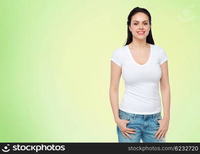 advertisement, clothing and people concept - happy smiling young woman or teenage girl in white t-shirt over green natural background