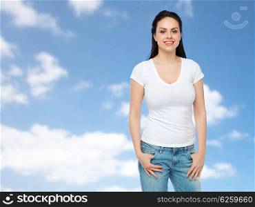 advertisement, clothing and people concept - happy smiling young woman or teenage girl in white t-shirt over blue sky and clouds background
