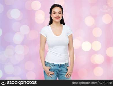advertisement, clothing and people concept - happy smiling young woman or teenage girl in white t-shirt over rose quartz and serenity holidays lights background