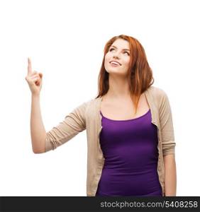advertisement concept - attractive teenager in casual clothes pointing her finger up