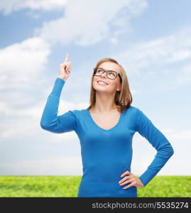 advertisement concept - attractive young woman in casual clothes and black eyeglasses pointing her finger up