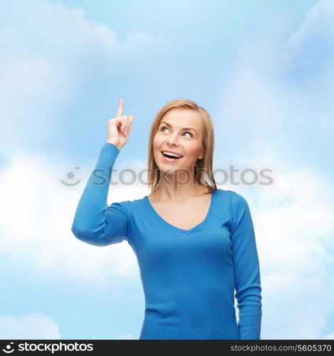 advertisement concept - attractive young woman in casual clothes pointing her finger up