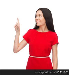 advertisement concept - attractive young woman in red dress pointing her finger up