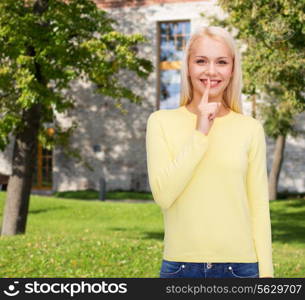 advertisement concept - attractive young woman with finger on her lip