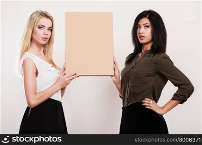 Advertisement concept. Two women caucasian and african holding blank board empty banner cardboard studio shot