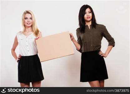 Advertisement concept. Two women caucasian and african with blank board empty banner cardboard studio shot