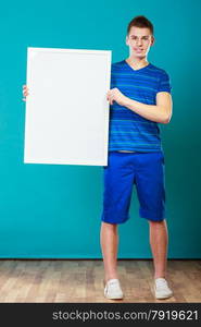 Advertisement concept. Young man holding blank presentation board. Male model showing banner sign billboard copy space for text on blue