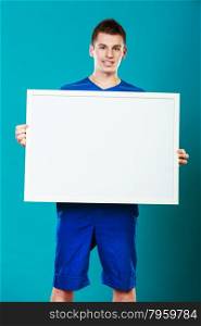 Advertisement concept. Young man holding blank presentation board. Male model showing banner sign billboard copy space for text on blue