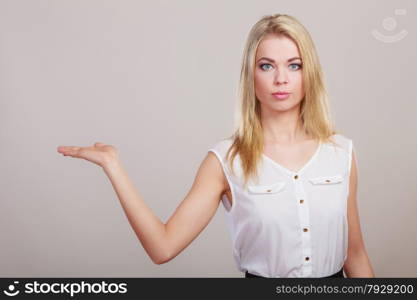 Advertisement concept. Young woman holding open palm empty hand showing copy space for product gray background