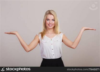 Advertisement concept. Young woman holding open palms empty hands showing copy space for product gray background