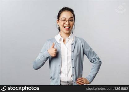 Advertisement, education and people concept. Girl guarantee you will like product. Potrait of lovely asian woman in glasses assure all good, show thumb-up in approval, recommend company service.. Advertisement, education and people concept. Girl guarantee you will like product. Potrait of lovely asian woman in glasses assure all good, show thumb-up in approval, recommend company service