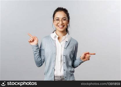 Advertisement, education and people concept. Girl recommends both products. Cheerful young asian woman in glasses pointing sideways, showing left and right promo with pleased smile.. Advertisement, education and people concept. Girl recommends both products. Cheerful young asian woman in glasses pointing sideways, showing left and right promo with pleased smile