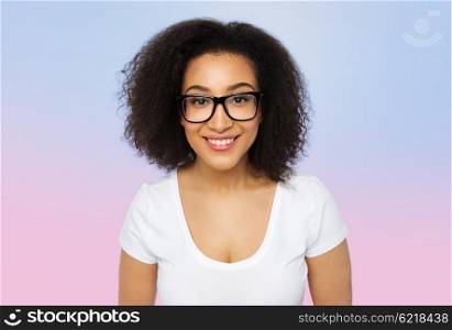 advertisement, education, ethnicity, vision and people concept - happy smiling young african woman in eyeglasses and white t-shirt over rose quartz and serenity gradient background