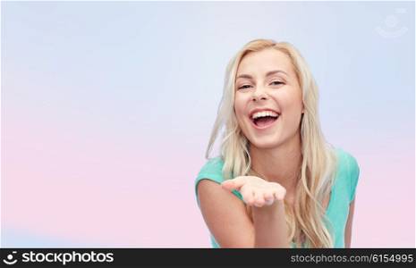 advertisement, emotions and people concept - smiling young woman or teenage girl holding something on hand over pink background